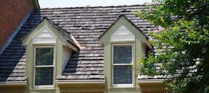 Two dormers in roof with wood shingles on a brick townhouse