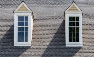 Two white wood dormers on a grey asphalt roof